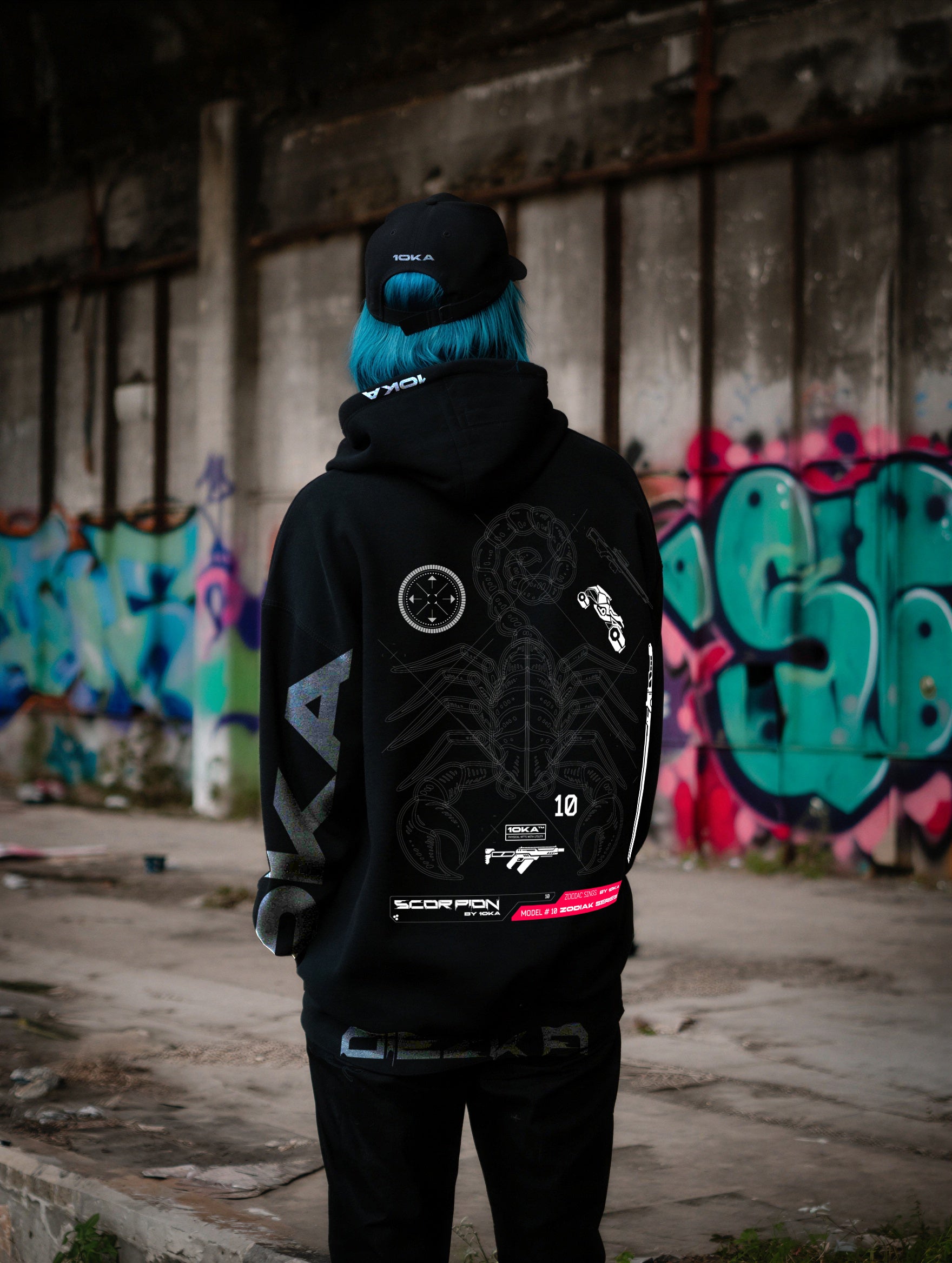 Model wearing the Zodiac Hoodie Scorpio by 10KA in an urban setting, back view, showcasing dark futuristic graphics inspired by Scorpio intensity and transformation.

